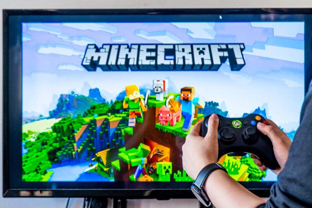 How to Fix a Corrupted Minecraft World or Restore From Backup image - Woman holding a xbox controller and playing popular video game minecraft on a television and PC