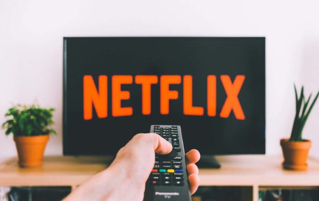 person holding a remote control pointed at a TV displaying the Netflix logo