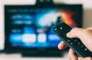 hand-holding-fire-tv-remote-with-a-blurred-TV-screen-in-the-background