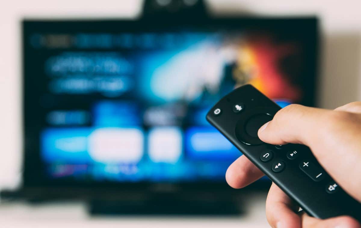 hand-holding-fire-tv-remote-with-a-blurred-TV-screen-in-the-background - hand-holding-fire-tv-remote-with-a-blurred-TV-screen-in-the-background