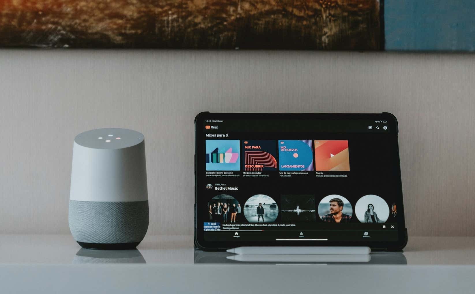 A Google Home Speaker sits next to an iPad with YouTube Music open on the screen - youtube-music-on-ipad