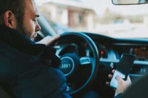 Person holding and staring a phone at the wheel of an Audi vehicle